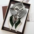 Dettaglio di un foulard in seta a righe geometriche verde scuro annodato in una scatola - Stile Geometrico a Righe Color Block (1) / 70x70cm