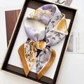 Close-up of elegant floral silk scarf with purple and yellow print in a golden tray - Orange