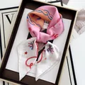 Detailed macro of floral twilly silk scarf tied in a premium brown gift box - Pink