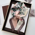 Détail d'un carré de soie avec imprimé floral et éclat satiné dans un coffret cadeau - Rose