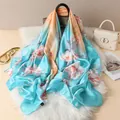 Close-up of floral silk scarf draped on a handbag with peach and blue petal patterns - Sky Blue