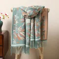 Detailed close-up of grey-blue floral jacquard scarf with orange patterns and fringes - Teal