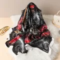 Fashionable long silk scarf with red feather print on black, draped over a leather bag - Black