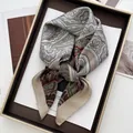 Detailed view of satin square scarf with paisley pattern in gold decorative tray - Khaki