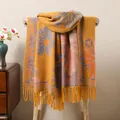 Detail of ethnic style scarf with vintage floral patterns and long tassels on a chair - Orange