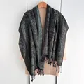 Ethnic paisley shawl in dark green and gold with black fringes on a wooden hanger - Black