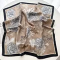 Gros plan d'un foulard en soie à fleurs élégant avec bordure noire sur table blanche - Champagne Bord Noir Floral (16)
