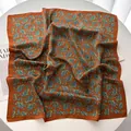 Square paisley silk scarf in rust orange with satin sheen on minimalist white desk - Coffee Paisley Style