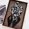 Détails d'un foulard carré en soie présentant des motifs paisley noirs et dorés - Noir