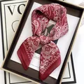 Detail eines roten Seidentuchs mit Paisleymuster in einer Geschenkbox auf einem Magazin - Paisley Schleife Stil (14) / Rot