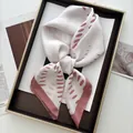 Primer plano de un pañuelo de seda anudado con textura suave y elegantes motivos rosados - Estilo de Estampado Ovalado Rosa Loto Blanco Roto (39) / Blanco Roto