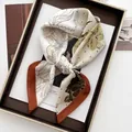 Detailed top view of silk square scarf with floral print and terracotta borders on a magazine - Beige Dark Orange Border Floral Style (34)