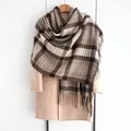 Detailed macro view of soft plaid cashmere scarf texture with classic brown fringe trim - Coffee
