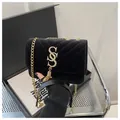 Dettaglio della borsa trapuntata in velluto nero con logo dorato, nappa e catena - Nero