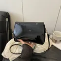 Bolso de hombro en charol negro brillante con solapa ondulada y detalles dorados - Negro