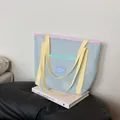 Blue mesh beach bag with pink trim and yellow straps on art books for modern lifestyle - Blue