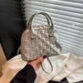 Silver shell-shaped handbag with quilted pattern and gold hardware on a modern background - Silver