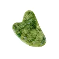 Dettaglio macro della pietra gua sha in giada naturale verde a forma di cuore levigato - Strumento Gua Sha a forma di cuore