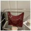 Close-up of wine red glossy faux leather shoulder bag with silver rivet details - Red