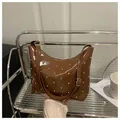 Detail of a brown glossy hobo bag with silver studs and adjustable metal buckle - Brown