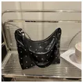 Detailed view of black patent leather hobo bag with silver studs on a stylish display - Black