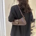 Dunkelbraune Baguette-Tasche mit Krokodilmuster und großer goldener Schnalle am Model - Braun