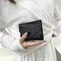 Piccolo portafoglio nero lucido con trama a coccodrillo tenuto da una modella - Nero