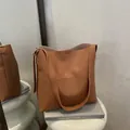 Chic brown leather shoulder bag with vertical stitching on minimalist art pedestal - Tan