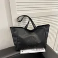 Große schwarze Leder-Einkaufstasche mit rundem Logo und langen Schultergurten - Schwarz