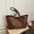 Dunkelbraune Tragetasche aus strukturiertem Kunstleder mit rundem Logo und zwei Henkeln - Braun
