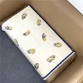 Detailansicht eines cremefarbenen Schals mit Federmuster und weißen Fransen auf dem Sofa - Beige mit Blauem Band