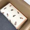 Detail eines cremefarbenen Schals mit orangefarbenem Federmuster und feinen Fransen - Beige Orange Kante