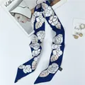 Detail of silk twilly scarf with camellia print and washing label on navy blue fabric - Blue