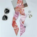 Plano detalle de pañuelo de seda rosa con estampado urbano, anillo de perla y gafas - Color 2 (Rosa Naranja Púrpura)