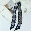 Detailed view of long navy blue silk scarf with golden chain patterns on a white shirt - Blue