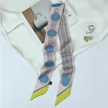 Detailed close-up of pink and blue chain pattern narrow silk scarf on white fabric - Pink