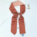 Detail of red and white geometric silk-like twilly scarf with washing label and gold earring - Color 6 (Dark Red Intertwined Triangle)
