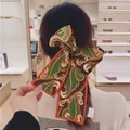 Fashionable satin silk scarf with vintage paisley pattern tied as a large hair bow - Orange Paisley Pattern