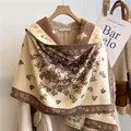 Dettaglio dello scialle in simil cashmere con motivo a farfalla su gruccia in legno - 180x65cm / caffè
