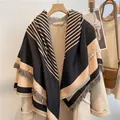 Detail of striped cashmere-like shawl with fringes hanging on a wooden hanger - Black Coffee