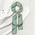Macro shot of green and white checkerboard satin scarf on beige silk dress - Green White Large Checkerboard Style
