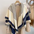 Striped cashmere-like scarf with tassels over a beige wool coat for winter style - Blue
