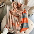 Close-up of thick butterfly pattern shawl with fringes and orange striped border - Khaki