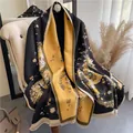 Detail of double-sided floral scarf with tassel edges on a beige sofa - Black