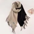 Detalle de una bufanda de punto suave con flecos y un diseño bicolor en negro y beige - Empalme Negro y Beige