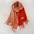 Detalle de la bufanda bicolor de cachemira con flecos y la etiqueta de la marca UNDERSO - Orange and Light Pink Orange
