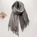 Primer plano detallado de bufanda de cachemira gris con flecos y etiqueta tejida elegante - Gris Medio