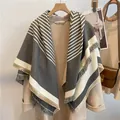 Thick grey and white striped wool scarf with fringe trim styled with a beige coat - Gray