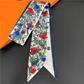 Close-up of a floral print silk hair ribbon with red poppy pattern and navy border - White