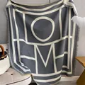 Detalle de manta de punto con diseño jacquard HOME y bordes acabados con flecos finos - Gris